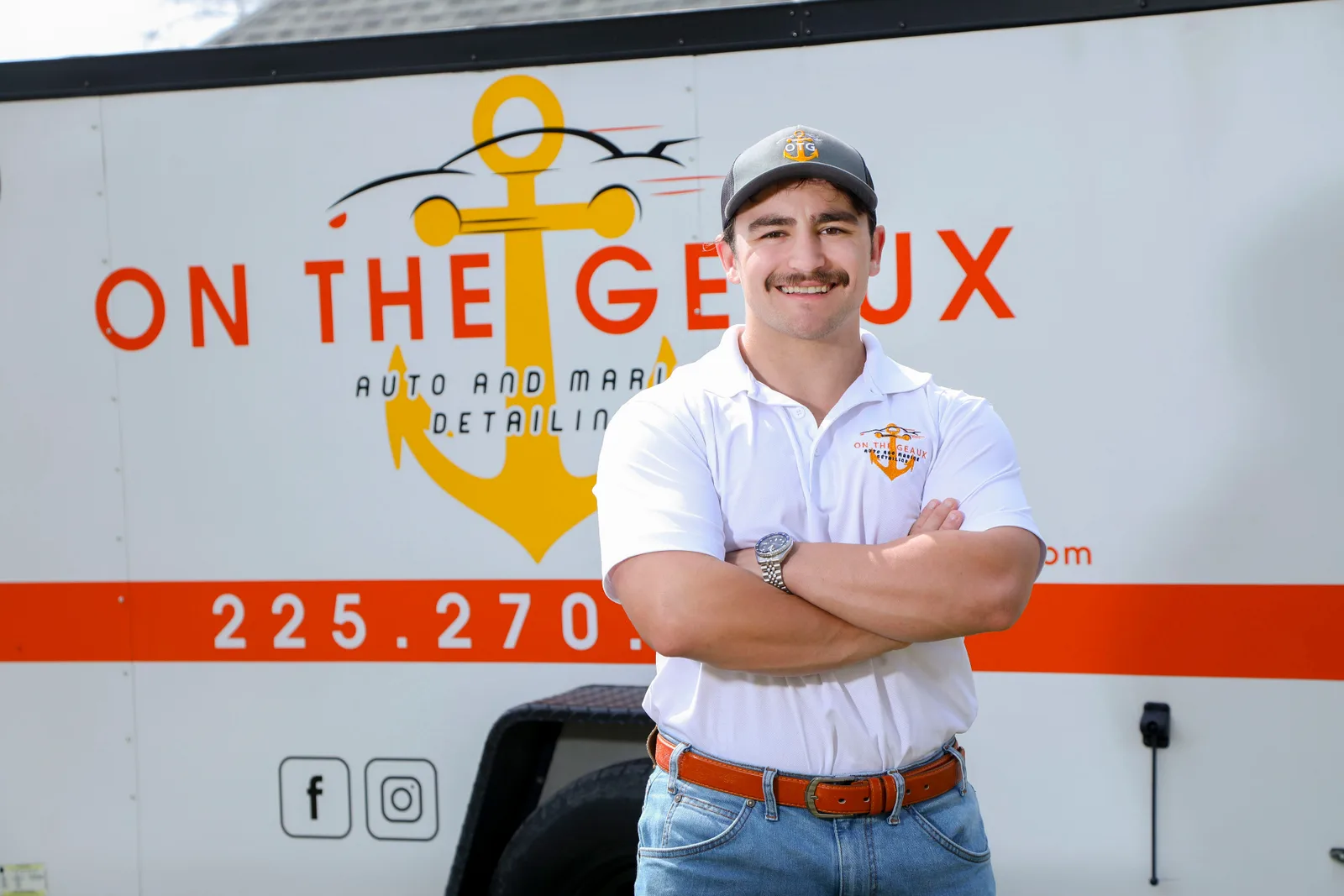 Hunter Goodson in branded apparel in front of the On The Geaux service trailer.