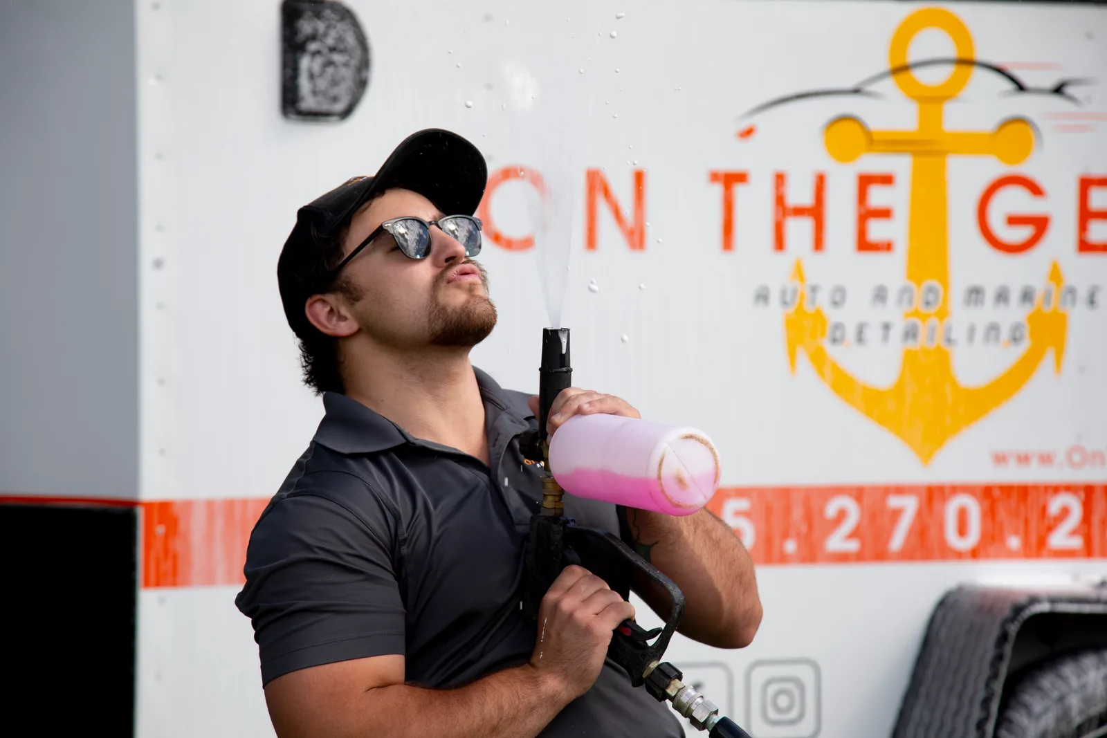 On The Geaux technician with a foam cannon in front of the branded mobile trailer.